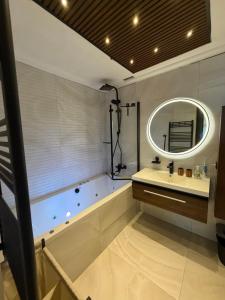 a bathroom with a tub and a sink and a mirror at Alamine plage in Fnidek