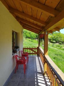 a porch with red chairs and a wooden roof at Casa Maria in Ciocaşu