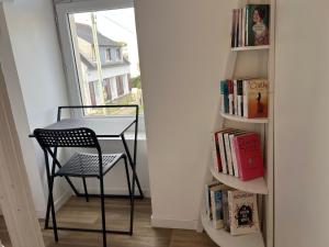 a table and chair next to a book shelf with books at Chambre salle d'eau privée in Brest