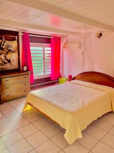 a bedroom with a large bed with pink curtains at appartement T2 cosy avec piscine in Baie-Mahault