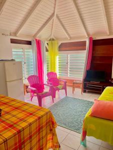 a room with colorful chairs and a table and a refrigerator at appartement T2 cosy avec piscine in Baie-Mahault