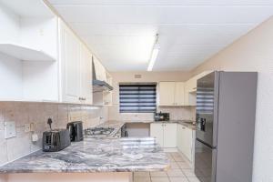 a kitchen with white cabinets and a stainless steel refrigerator at 3 bed ground in sandton in Johannesburg