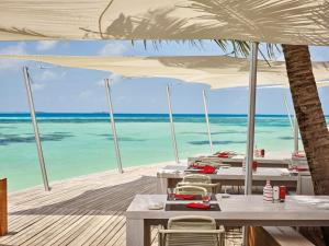 a beach area with chairs, tables and umbrellas at LUX* South Ari Atoll Resort & Villas in Maamigili