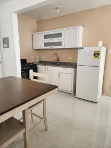 a kitchen with a white refrigerator and a table at 2BR Apartment, Blue Ocean Suites, Manati in Manati