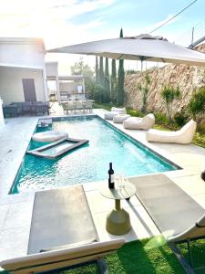 a swimming pool with chairs and an umbrella at Villa Casa Blanca in Kefar H̱ananya