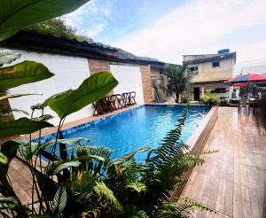 a swimming pool in front of a building with plants at My House Muriqui in Mangaratiba