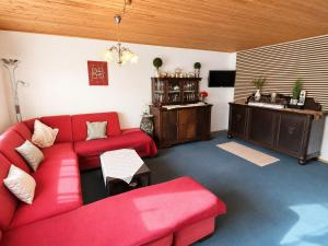 a living room with a red couch and a sink at Käthe's Gästezimmer in Reimerath