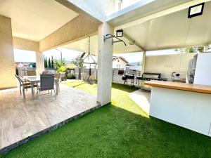 a patio with green grass and a kitchen and a table at Villa Casa Blanca in Kefar H̱ananya