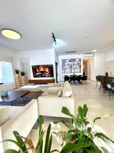 a living room with white furniture and a large tv at Villa Casa Blanca in Kefar H̱ananya