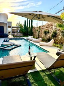 a swimming pool with chairs and an umbrella at Villa Casa Blanca in Kefar H̱ananya