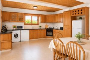 a kitchen with a table and a white refrigerator at Villa Chrisandria in Argaka