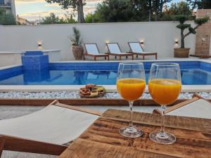 two glasses of wine sitting on a table next to a pool at Mare Vista Rooftop Penthouse Sea View & Private Jacuzzi in Trogir