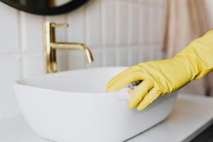 a person in yellow rubber gloves cleaning a sink at Le Ponsardin in Reims