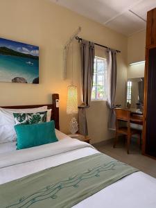 a bedroom with a bed and a desk and a window at Maison Charme De L'ile in La Digue +63 photos