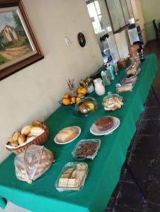a long green table topped with lots of different types of bread at Pousada Sant`Ana in Sabará