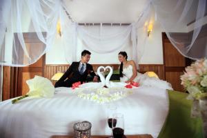 a bride and groom sitting on a bed at NATAYA Round House Coral Bay Resort in Kampot