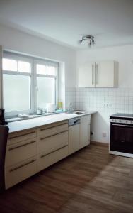 a kitchen with white cabinets and a sink and a window at FeWoLaqua in Leipzig