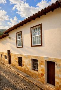 a house with three windows on a cobblestone street at Casa Completa No Centro Para Famílias e Grupos Até 9 Hospedes Com Garagem in Ouro Preto