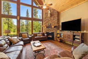 a living room with a stone fireplace and a television at Destiny Luxury Log Cabin in Sturgis