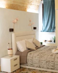 ein Schlafzimmer mit einem Bett, einem Nachttisch und zwei Fenstern in der Unterkunft QUART0 GREC0 Suite 15 in Altamura