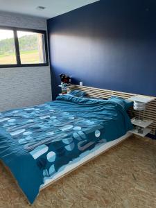a bedroom with a bed and a blue wall at Villa Millau-gorges du Tarn in Aguessac