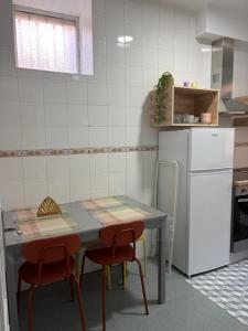 a kitchen with a table and two chairs and a refrigerator at Apartamento Nordés in A Guarda