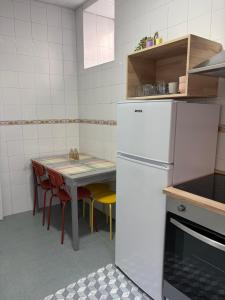a kitchen with a white refrigerator and a table with chairs at Apartamento Nordés in A Guarda +3 photos