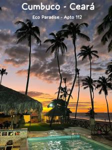 a resort with a pool and palm trees at sunset at CUMBUCO - Eco Paradise - AP 112 - Rezende temporada in Cumbuco