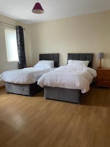 two beds in a room with wood floors at Breesy Centre Apartment in Donegal