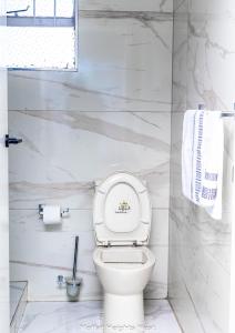 a white toilet in a bathroom with white marble walls at MoffatHeights Nest in Harare