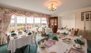 韋斯特波特的住宿－Carrabaun House，一间设有白色桌椅和窗户的用餐室