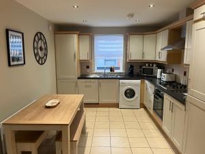 a kitchen with white cabinets and a table in it at Old Schoolhouse Coleraine in Coleraine