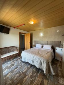 a bedroom with a large bed with a wooden ceiling at Hotel e Restaurante Santa Fé in Lages
