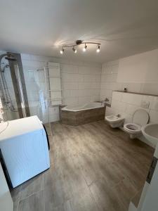a bathroom with two toilets and a tub and a sink at Monteurzimmer Ferienwohnung in Bad Gandersheim