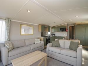 a living room with two couches and a kitchen at The Swift in St Bees