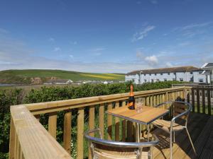 a table and chairs on a deck with a bottle of wine at The Swift in St Bees