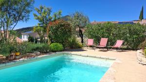 a swimming pool with two pink chairs next to a yard at La benvingude CH d'hôte in Nyons