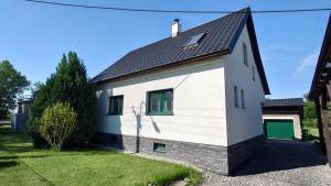 a white house with a black roof at Dům in Hrabowa
