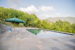 a swimming pool with an umbrella and a chair and a table and an umbrella at Villa Eremo Cinque Terre in Castiglione Chiavarese