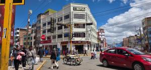 a building on a busy city street with people crossing the street at Hatun Wasi Puno in Puno