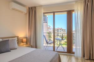 a bedroom with a bed and a balcony with a table at Infinity View 3 Shkorpilovci in Shkorpilovtsi