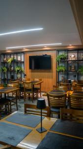 a restaurant with tables and chairs and a flat screen tv at Nohotel Nova Odessa in Nova Odessa
