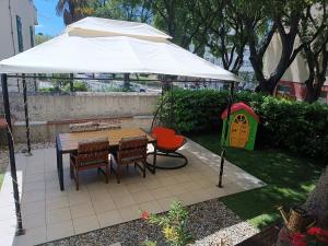 a table and chairs under an umbrella with a play house at Garden apartment Vanya in Split