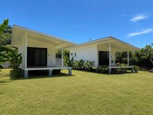 a small white house with a grass yard at Au Petit Bungalow - Air conditionned & Mountain view in Moorea