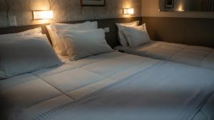 two beds in a room with white sheets and pillows at Nohotel Nova Odessa in Nova Odessa