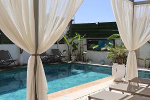 a pool with curtains and chairs and a swimming pool at My Angels Alaçatı in Alaçatı