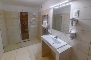 a white bathroom with a sink and a shower at Az Idill in Cserszegtomaj +3 photos