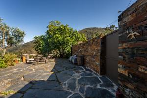 a patio with two chairs and a brick wall at Casa da Figueira - Rio Paiva in Arouca