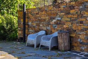 two chairs and a stump next to a brick wall at Casa da Figueira - Rio Paiva in Arouca