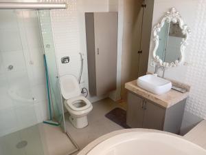 a bathroom with a toilet and a sink and a mirror at Refúgio Urbano Amplo e Luxuoso in Imperatriz